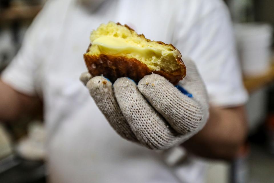 Nassar Alriyashi test tastes a custard-filled paczki while making them, during Paczki Day at the Family Donut Shop in Hamtramck on March 1, 2022.