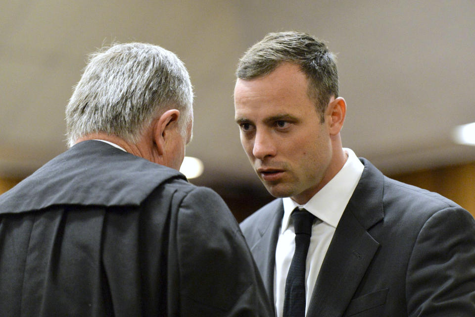 Oscar Pistorius, right, speaks with his lawyer Barry Roux as the start of his trial is delayed at the high court in Pretoria, South Africa, Monday, March 3, 2014. Pistorius is charged with murder with premeditation in the shooting death of girlfriend Reeva Steenkamp in the pre-dawn hours of Valentine's Day 2013. (AP Photo/Herman Verwey, Pool)