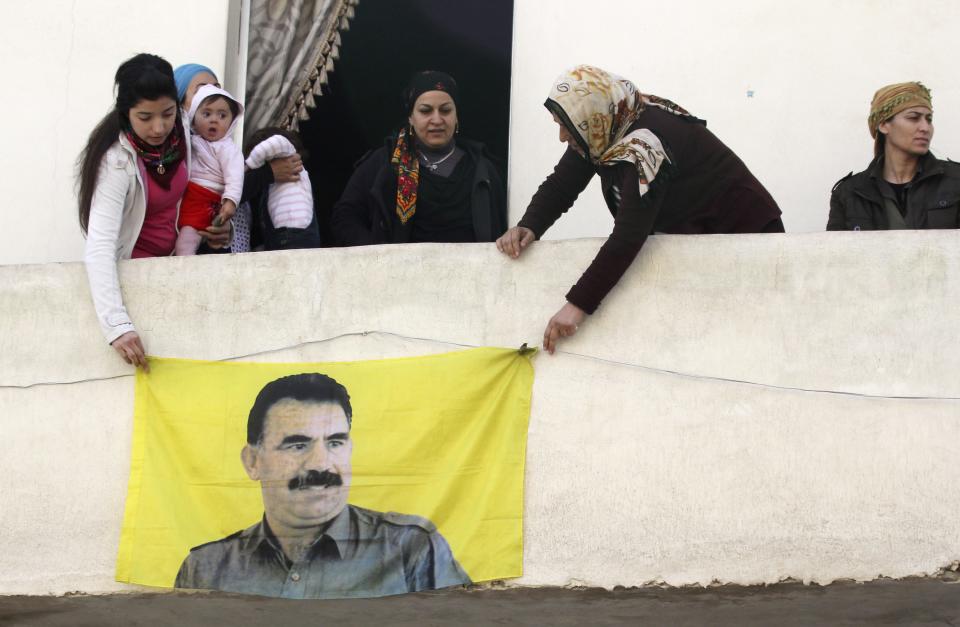 Kurdish women hang picture of Abdullah Ocalan, jailed leader of PKK, during celebration after it was reported that Kurdish forces took control of Kobani, in Aleppo