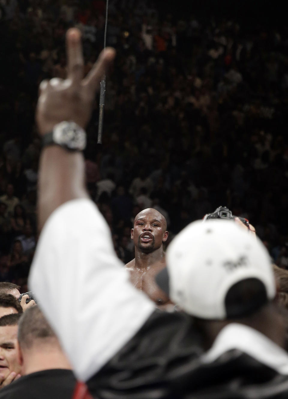 A member of his corner flashes a victory sign as Floyd Mayweather Jr. reacts at the end of his WBC-WBA welterweight title boxing fight against Marcos Maidana Saturday, May 3, 2014, in Las Vegas. Mayweather won the bout by majority decision. (AP Photo/Isaac Brekken)