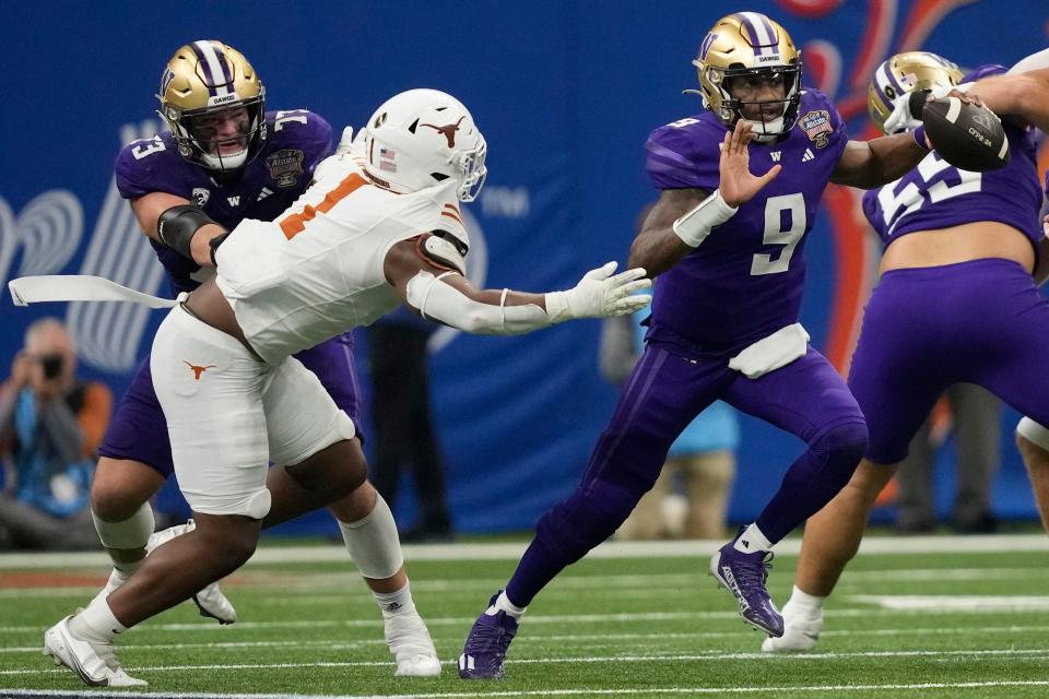 Washington quarterback Michael Penix Jr. (9) scrambles with the ball against Texas defensive end Justice Finkley (1) during the second half of the Sugar Bowl CFP NCAA semifinal college football game, Monday, Jan. 1, 2024, in New Orleans. (AP Photo/Gerald Herbert)