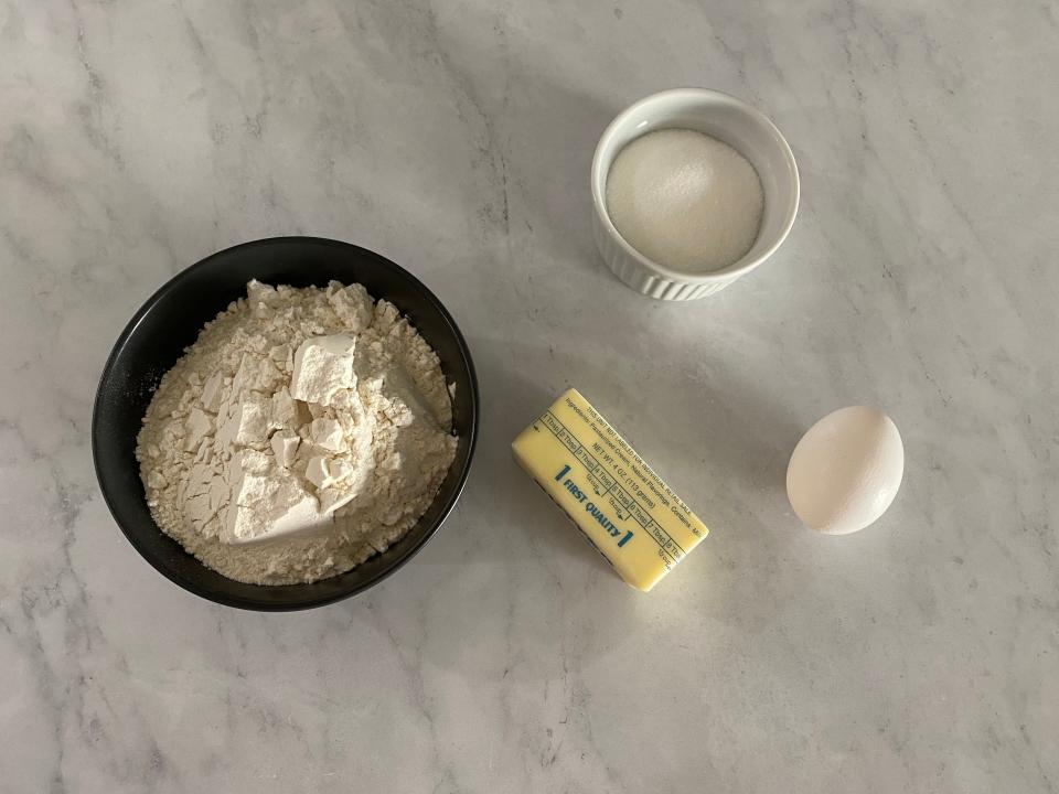 Flat lay of butter, sugar, cinnamon, and an egg.