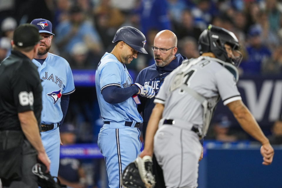 Toronto Blue Jays' George Springer, center, is looked at by staff after getting hit by a pitch during the third inning during third inning of a baseball game against the Toronto Blue Jays in Toronto, Wednesday, April 26, 2023. (Andrew Lahodynskyj/The Canadian Press via AP)