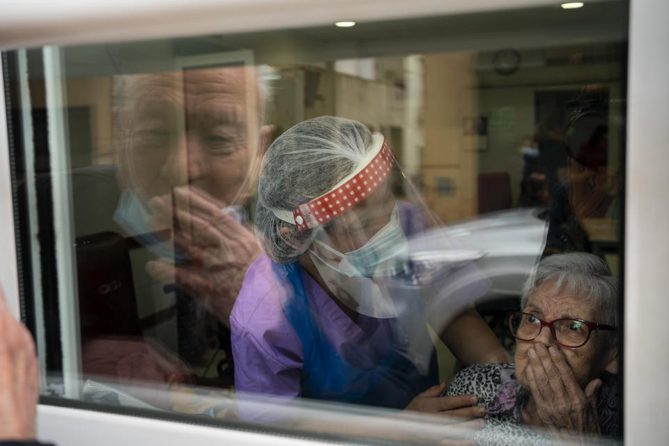 Javier Anto, 90, and his wife Carmen Panzano, 92, blow one another kisses through the window separating the nursing home from the street in Barcelona, Spain, Wednesday, April 21, 2021. Since the pandemic struck, a glass pane has separated _ and united _ Javier and Carmen for the first prolonged period of their six-decade marriage. Anto has made coming to the street-level window that looks into the nursing home where his wife, since it was closed to visits when COVID-19 struck Spain last spring. (AP Photo/Emilio Morenatti)