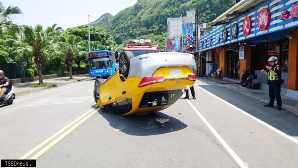 一輛計程車擦撞停放路旁的轎車後翻覆，四輪朝天的橫躺在車道上。（記者趙智偉翻攝）