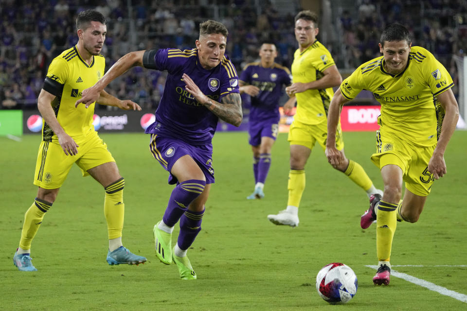 Orlando City's Gaston Gonzalez, center, makes a move to get past Nashville SC's Daniel Lovitz, left, and Sean Davis, right, during the second half of an MLS soccer match, Saturday, April 1, 2023, in Orlando, Fla. (AP Photo/John Raoux)