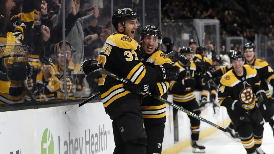 Teammates pile off the bench as Boston Bruins' Patrice Bergeron, left, celebrates his game-winning goal with Brad Marchand in their 5-4 overtime win over the Los Angeles Kings in an NHL hockey game Saturday, Feb. 9, 2019, in Boston. (AP Photo/Winslow Townson)