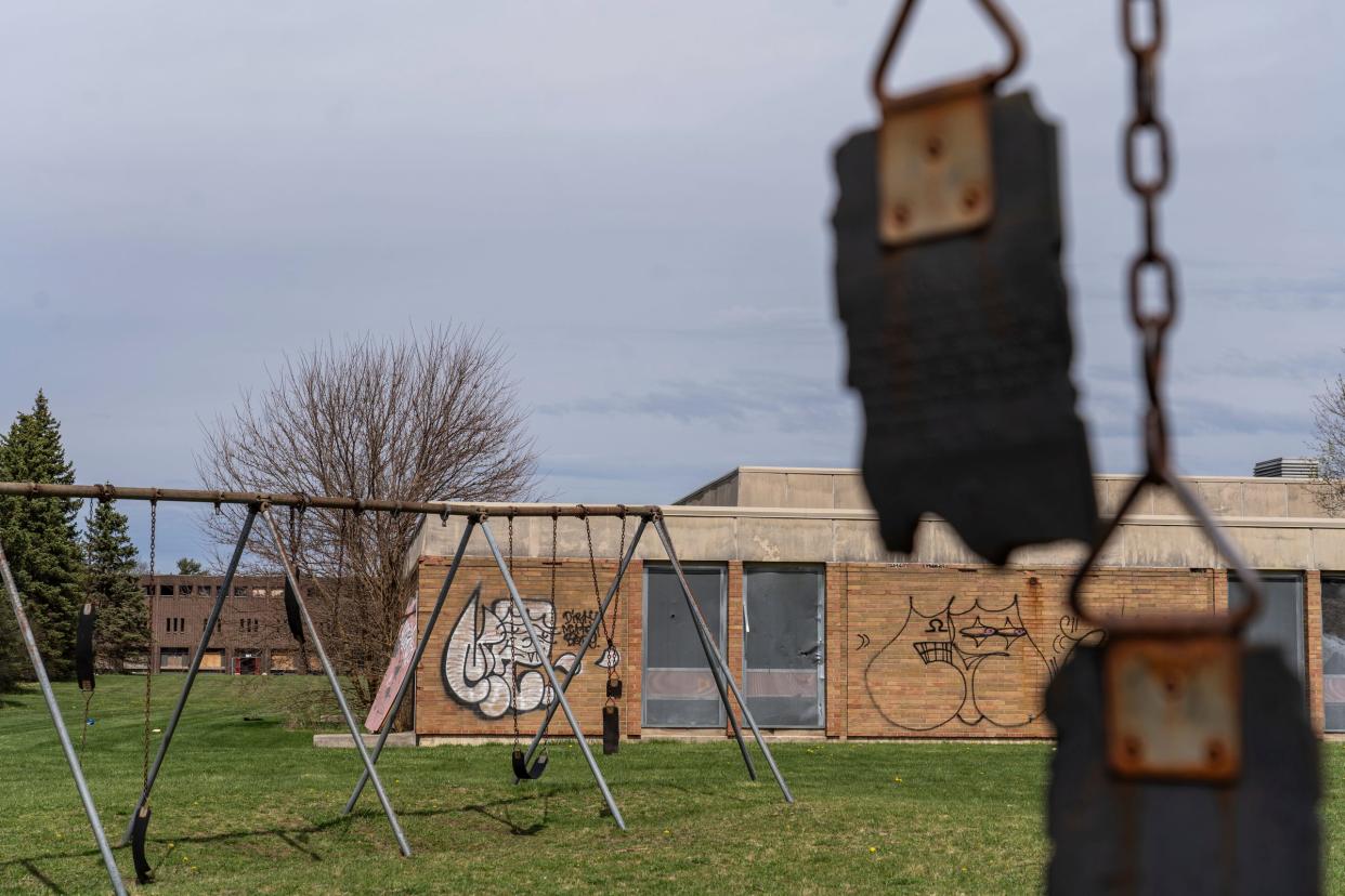 Broken swings hang from chains outside of the former Anderson Elementary School in Flint, which sits abandoned in front of the closed and abandoned Flint Northern High School, left, on Thursday, April 18, 2024.