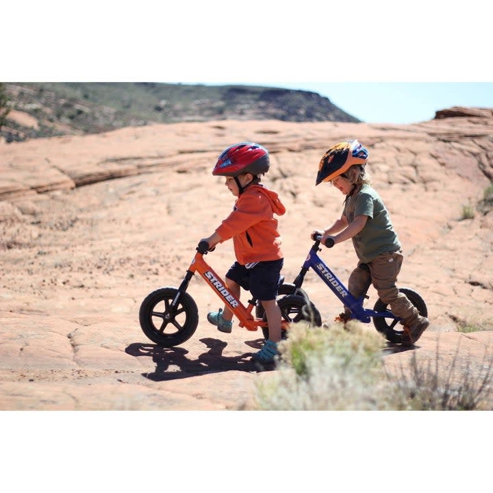 Two kids riding balance bike outdoors