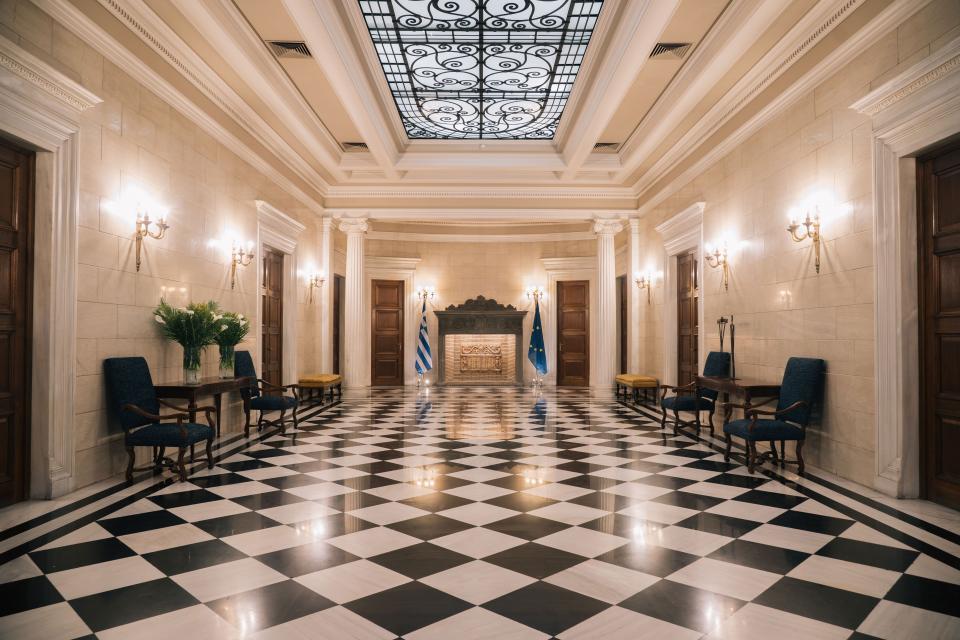 The hallway of the Maximos Mansion, which was built in 1921. The table on the right holds Oedipus and Antigone, two iron-and-wood figures by Takis.