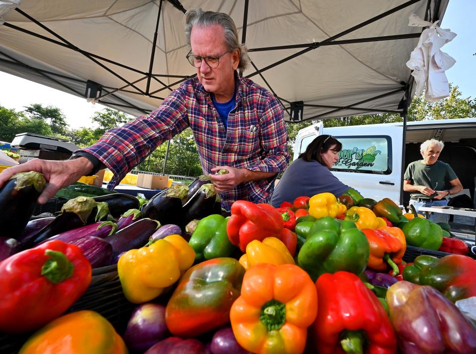 Mark Lyn and Paula Harper of Harper's Farm and Garden of Lancaster add more produce to their stand at the REC Community Farmers Market at Beaver Brook Park on Friday.