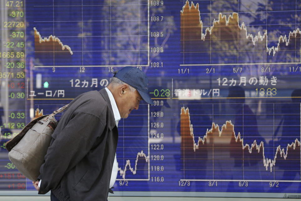 In this Thursday, Nov. 21, 2019, photo, a man walks by an electronic stock board of a securities firm in Tokyo. Stocks logged modest gains Friday, Nov. 22, 2019, in Asia after a lackluster overnight session on Wall Street ended with the market’s third straight drop. (AP Photo/Koji Sasahara)