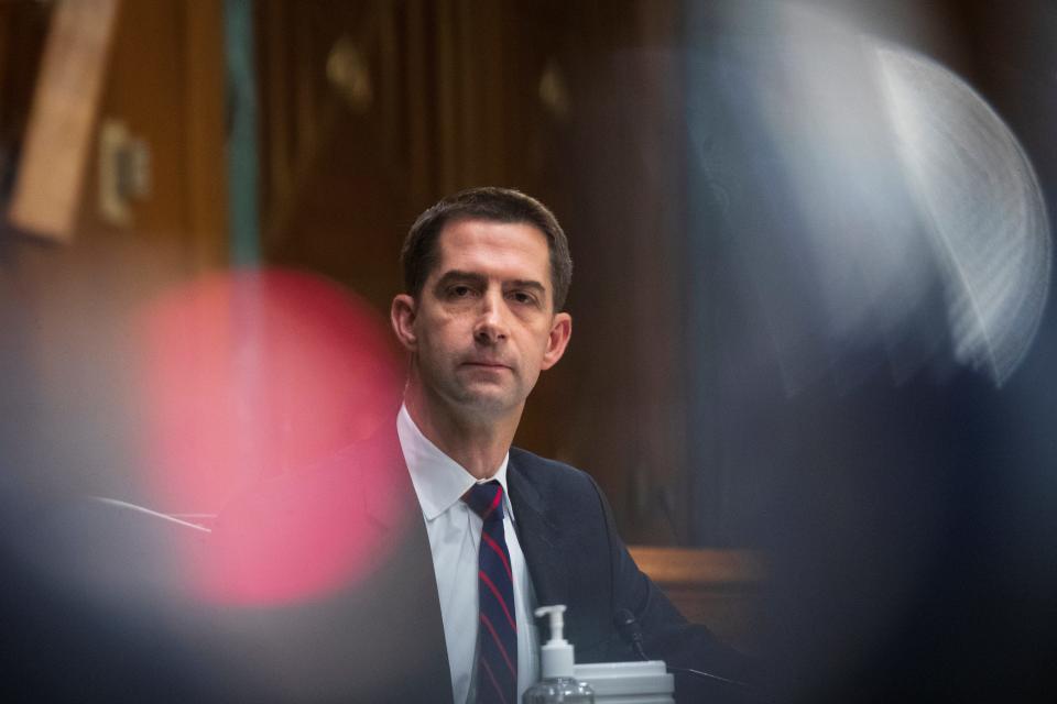Senator Tom Cotton, a Republican from Arkansas, sits and stares with a red flashing light next to him. He wears a suit and tie.