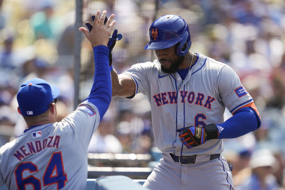 New York Mets' Starling Marte celebrates with manager Carlos Mendoza (64) after hitting a home run during the sixth inning of a baseball game against the Los Angeles Dodgers in Los Angeles, Saturday, April 20, 2024. Zack Short and Brandon Nimmo also scored. (AP Photo/Ashley Landis)