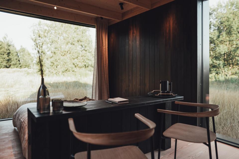 An expansive picture window frames views of the natural landscape in the bedroom area, where the headboard doubles as a bar for the dining space.