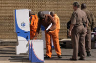 An officer watches on as an inmate inserts his ballot paper into the ballot box at the polling station at Kgoši Mampuru Correctional Facility in Pretoria, South Africa, Wednesday, May 29, 2024. South Africans voted Wednesday at schools, community centers, and in large white tents set up in open fields in an election seen as their country’s most important in 30 years. It could put the young democracy in unknown territory. (AP Photo/Themba Hadebe)