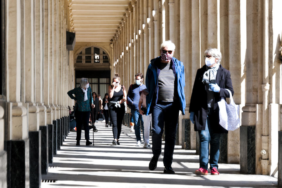 Paris : People walking under arch, near Comédie française, Palais Royal, colonnes de Buren, during epidemic Covid19 in Europe. This life scene is few days after the Covid 19 lockdown during spring 2020.  Paris in France, May 16th, 2020.