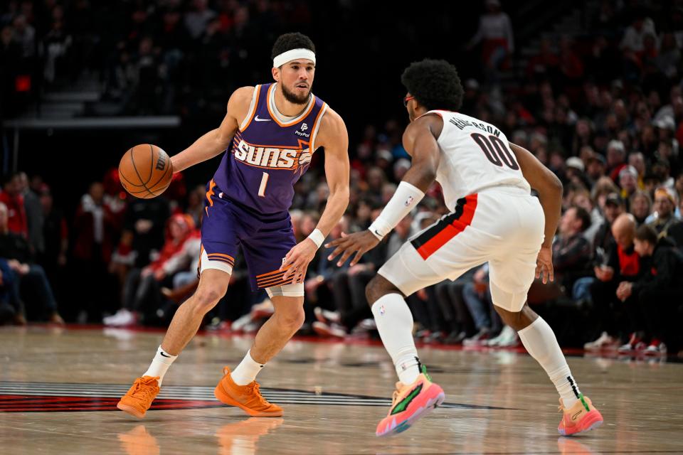 Devin Booker #1 of the Phoenix Suns dribbles against Scoot Henderson #00 of the Portland Trail Blazers during the fourth quarter of the game at the Moda Center on Dec. 19, 2023, in Portland, Oregon. The Portland Trail Blazers won 109-104.