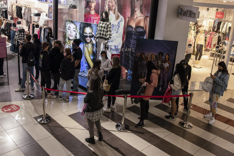 Consumers line up to enter a clothing store at a shopping center in the city of Beersheba, southern Israel, Sunday, Feb. 21, 2021. Israel lifted many of its coronavirus restrictions and started reopening its economy Sunday as the country's vaccination drive and third nationwide lockdown have started to bring down infections. (AP Photo/Tsafrir Abayov)