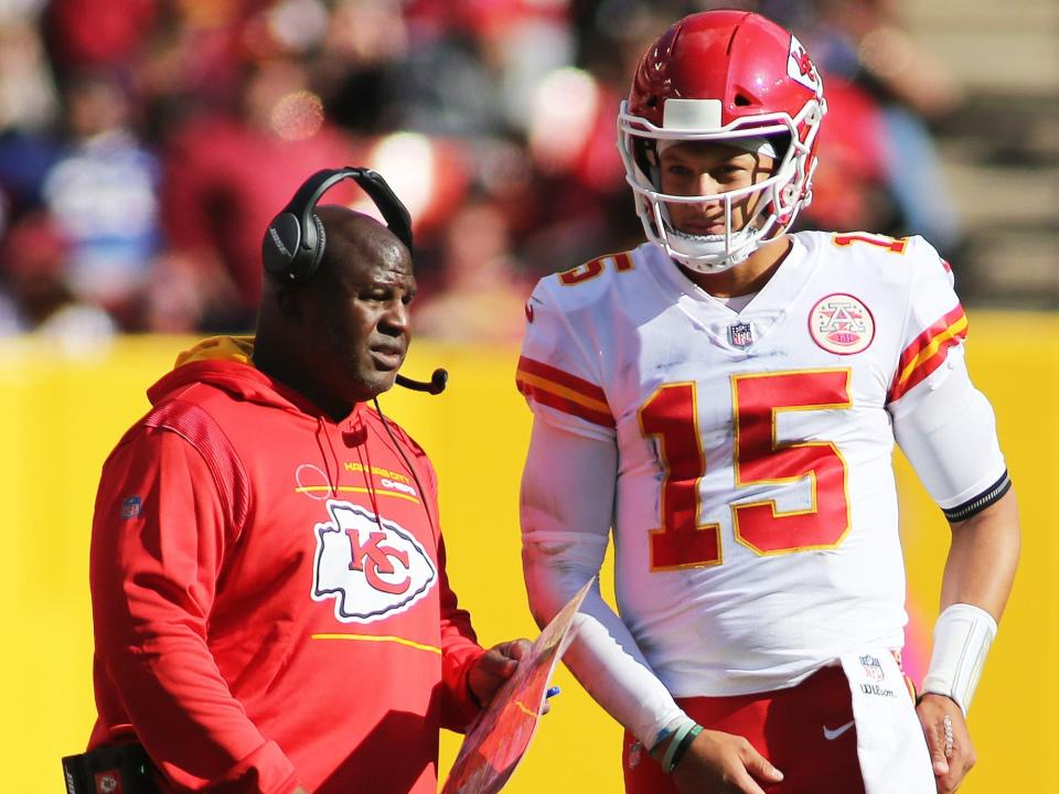 Eric Bieniemy talks to Patrick Mahomes on the field during a game in 2021.