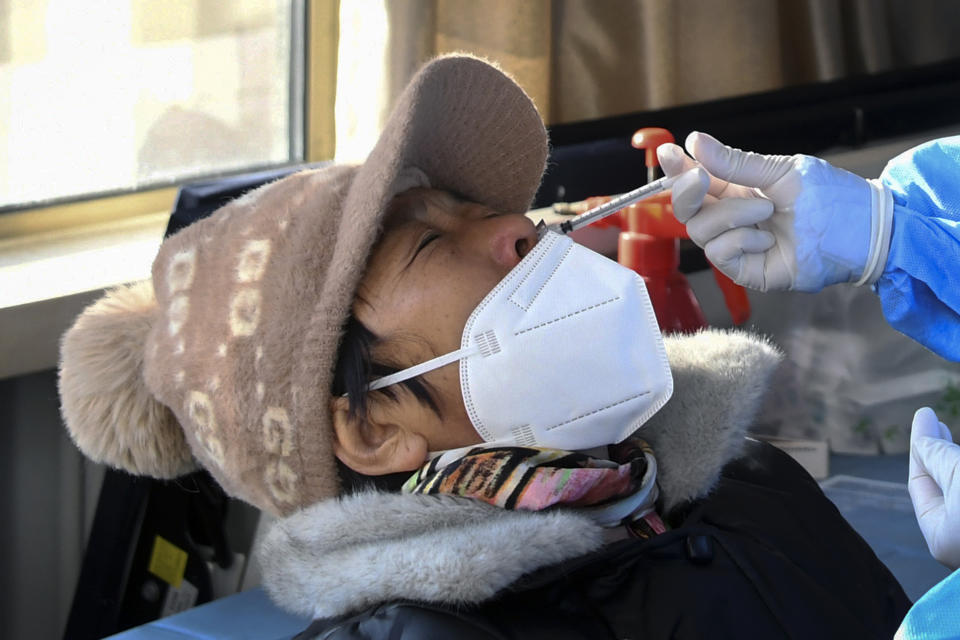 In this photo released by Xinhua News Agency, a woman wearing a face mask receives a second booster dose of COVID-19 vaccine through the nose, at a temporary vaccination site in Beijing, Saturday, Dec. 17, 2022. Chinese health authorities on Monday, Dec. 19, 2022 announced two additional COVID-19 deaths, both in the capital Beijing, that were the first reported in weeks and come during an expected surge of illnesses after the nation eased its strict "zero-COVID" approach. (Ren Chao/Xinhua via AP)