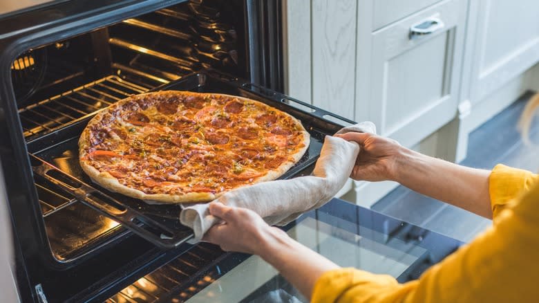 Woman taking pizza from oven