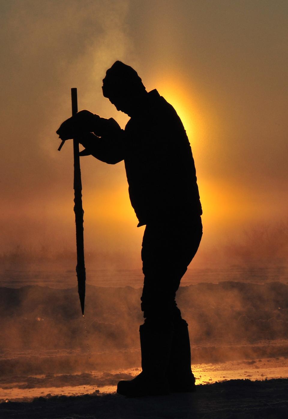 A worker stabs an iron pike into the frozen Songhua River as he extracts giant ice cubes to make sculptures for the upcoming 30th Harbin Ice and Snow Festival, in Harbin