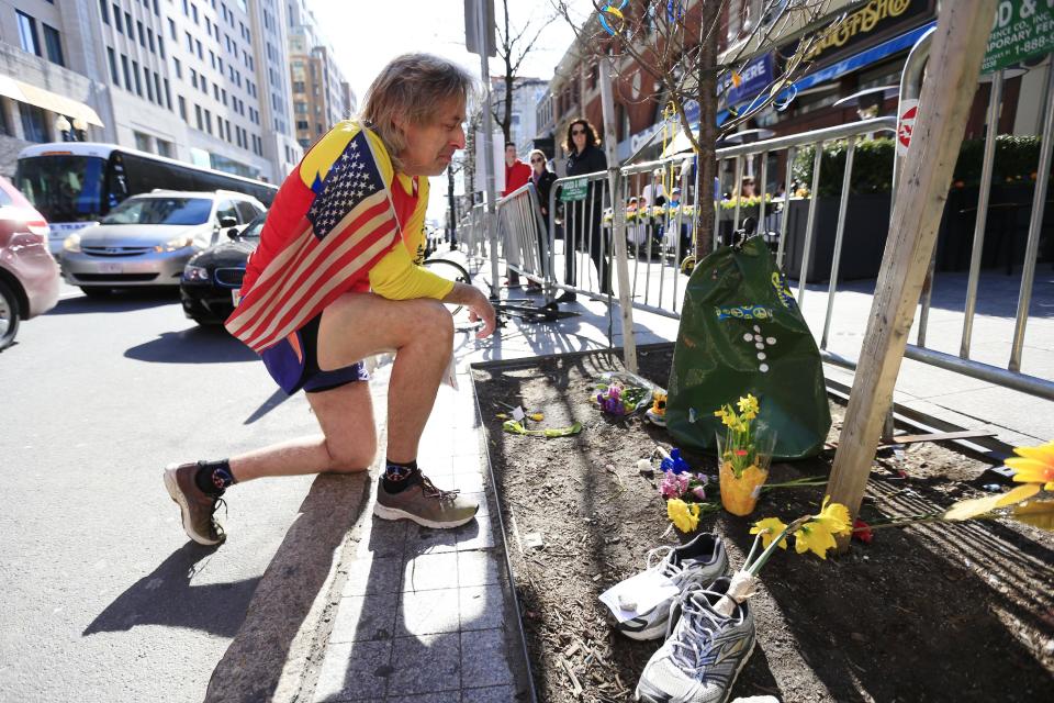 Ron McCracken of Dallas pays his respects at a makeshift memorial honoring to the victims of the 2013 Boston Marathon bombings ahead of Monday's 118th Boston Marathon, Sunday, April 20, 2014, in Boston. McCracken's race last year was cut short due to bombings and Monday's race will mark his 14th year running in the Boston Marathon. The memorial is where the second of two explosions happened last year near the finish line. (AP Photo/Matt Rourke)