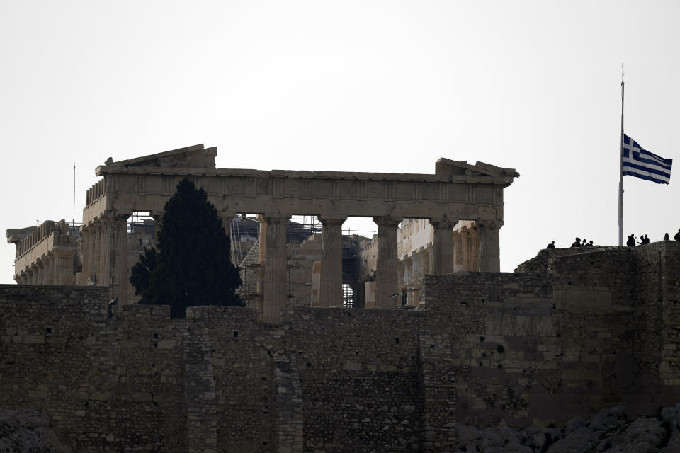 The flag on the Acropolis hill flies at half-staff in Athens, Wednesday, March 1, 2023 after three days of national mourning declared for the victims of the deadly train collision in Tempe. A head-on collision between a passenger train and a freight train flattened carriages, killing and injured dozens of passengers. (AP Photo/Thanassis Stavrakis)