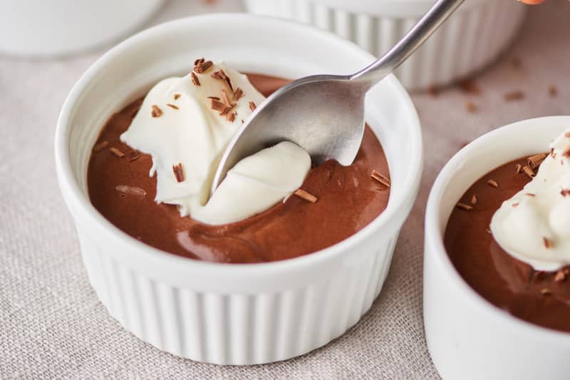 Chocolate mousse in a ramekin with spoon taking out a bite