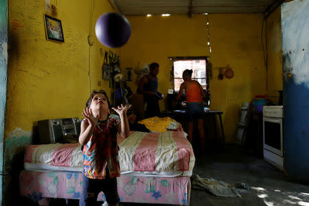 Emmanuel Cuauro, 4, plays with a ball next to his parents Zulay Pulgar (R), 43, and Maikel Cuauro, 30, in their house in Punto Fijo, Venezuela November 17, 2016. Picture taken November 17, 2016. REUTERS/Carlos Garcia Rawlins