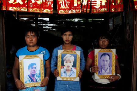 Women pose while holding portraits of their killed relatives (L-R) Aik Sai, Aik Maung and Aik Lort after their bodies were found in a grave last June at Mong Yaw village in Lashio, Myanmar July 10, 2016. REUTERS/Soe Zeya Tun