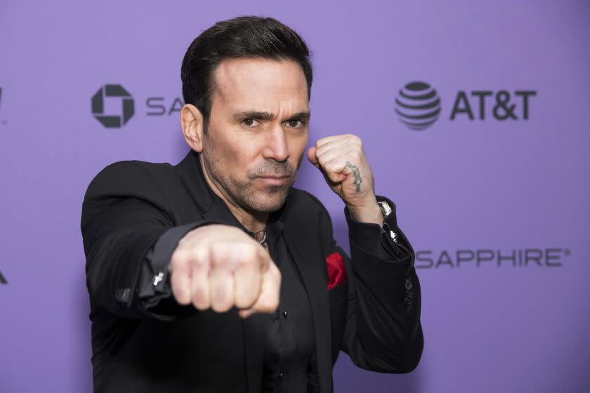 A man in a suit strikes a fighting pose on a red carpet