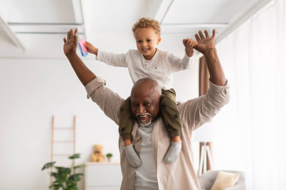 Happy grandpa carries grandson on shoulders