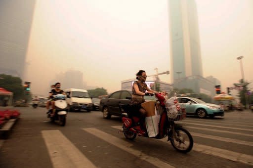 Chinese motorists wear masks as they make their way along a busy intersection in Wuhan on June 11. Wuhan was blanketed by thick yellowish cloud Monday, raising fears of pollution among its nine million inhabitants, residents told AFP. Witnesses said the haze appeared suddenly in the morning, and residents rushed to put on face masks