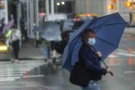 Pedestrians use umbrellas to protect themselves from inclement weather brought about by Tropical Storm Fay, Friday, July 10, 2020, in New York. Beaches closed in Delaware and rain lashed the New Jersey shore as fast-moving Tropical Storm Fay churned north on a path expected to soak the New York City region. (AP Photo/Frank Franklin II)