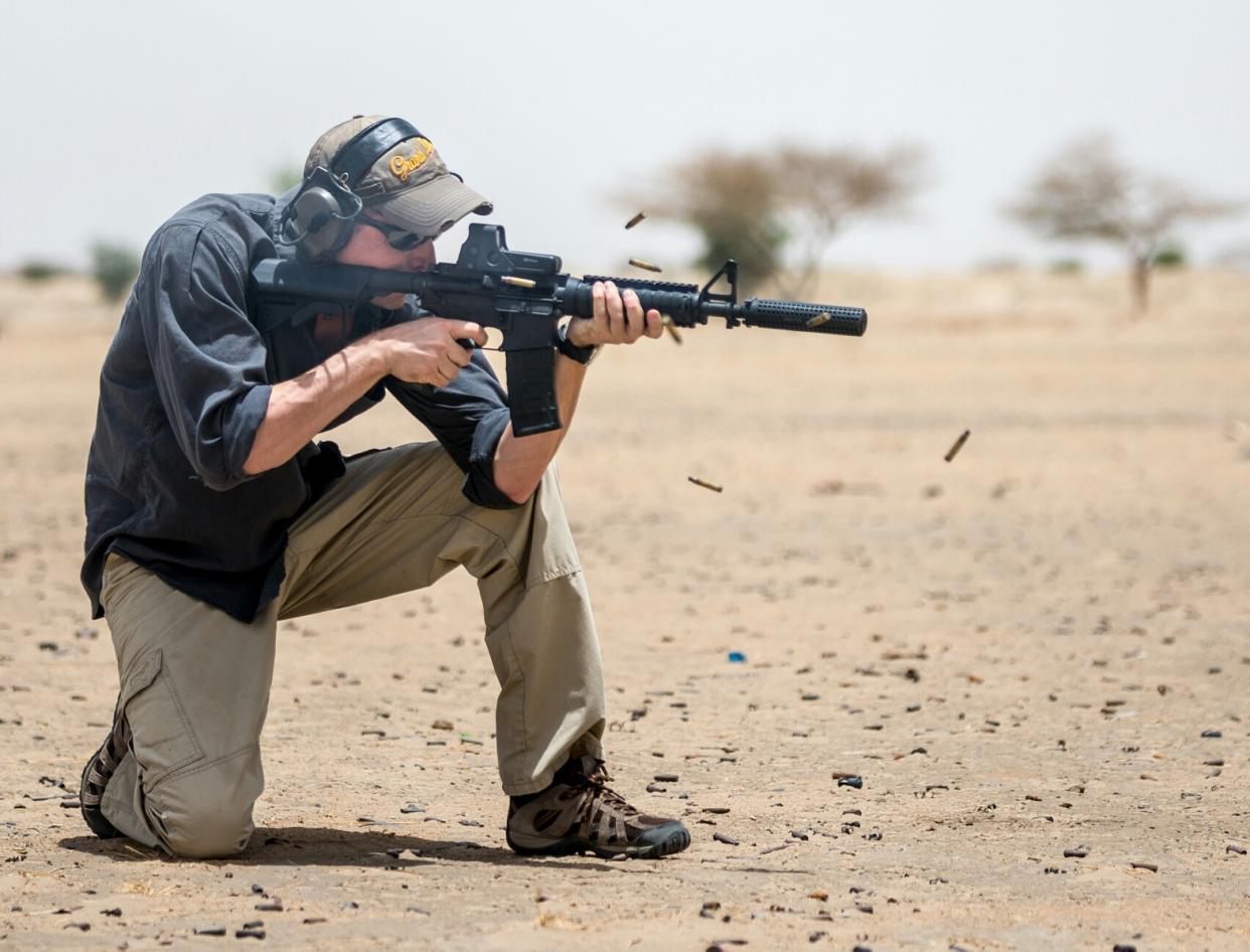 Michael Froede kneeling on the ground holding a weapon.