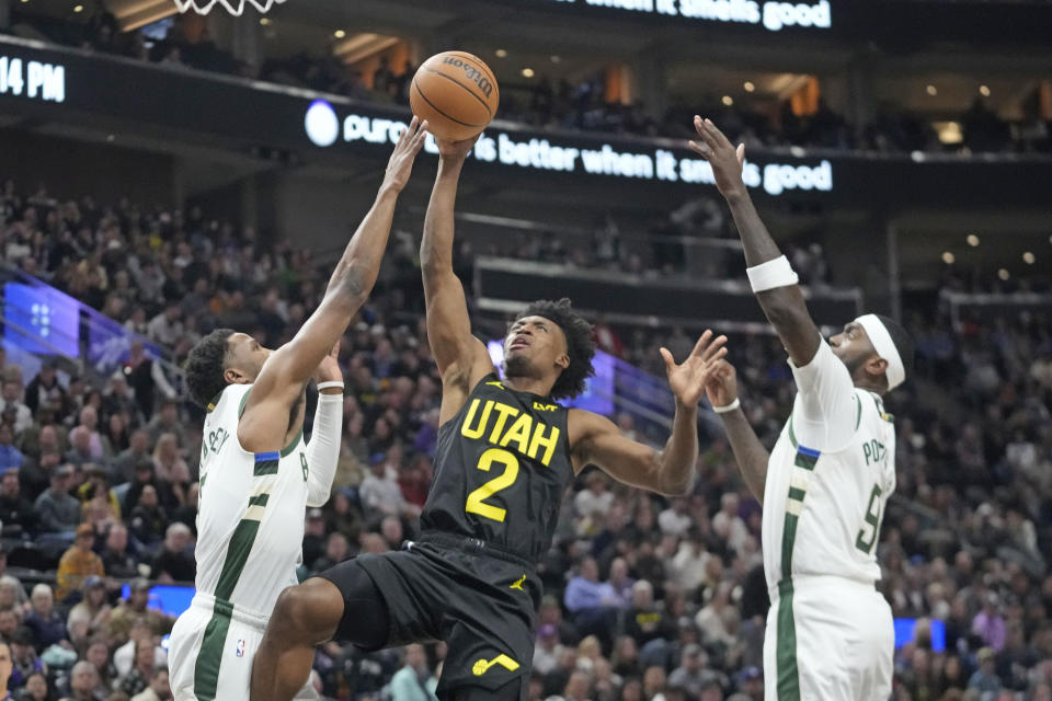 Milwaukee Bucks' Malik Beasley, left, and Bobby Portis, right, defend against Utah Jazz guard Collin Sexton (2) who shoots during the first half of an NBA basketball game Sunday, Feb. 4, 2024, in Salt Lake City. (AP Photo/Rick Bowmer)