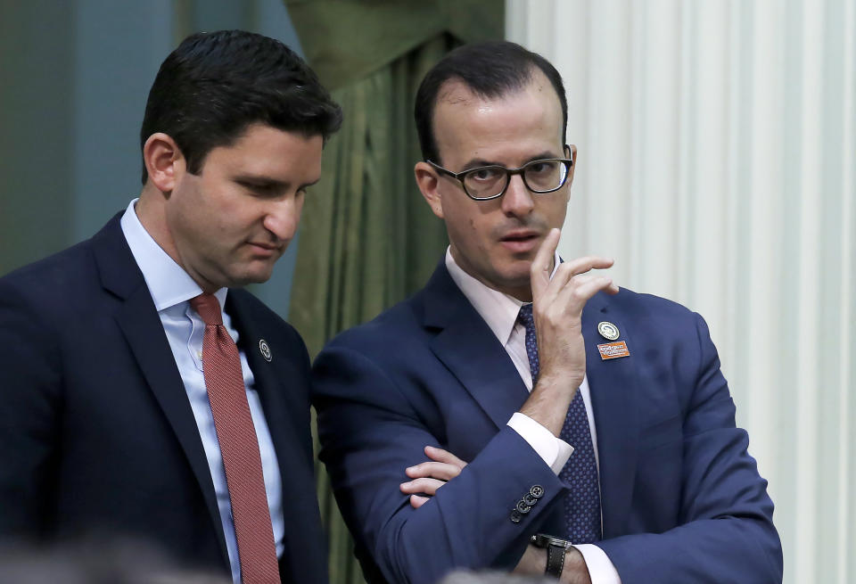 FILE - In this Sept. 10, 2019 file photo, Assemblyman Marc Berman, D-Palo Alto, right, talks with Assemblyman Jesse Gabriel, D-Encino, left, at the Capitol in Sacramento, Calif. Gov. Gavin Newsom announced Thursday Oct. 3, 2019, that he signed Berman's measure banning so-called "deep fake" videos designed to manipulate a political candidate's words or actions in the lead up to elections, It's a response to fears of dirty campaigning during the upcoming presidential race, but also a proposal that raises concerns about censorship and the First Amendment. (AP Photo/Rich Pedroncelli, File)