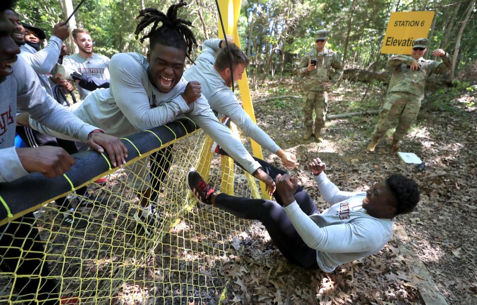 Zach Edwards and Francis Sherman react as teammate Yaya Diaby falls back into a pretend mine pit while the Louisville football players participate in a team-building exercise on the Fort Knox Base recently. June 16, 2021.