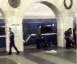 In this grab taken from AP video, Russian police officer, left, and people walk past the damaged train at the Tekhnologichesky Institut subway station in St.Petersburg, Russia, Monday, April 3, 2017. The subway in the Russian city of St. Petersburg is reporting that several people have been injured in an explosion on a subway train. (AP video via AP)