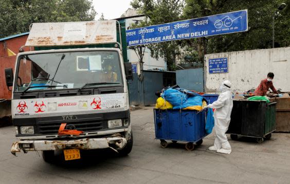 A medical staff member pushes a trolley containing medical waste bags to a storage area (Reuters)