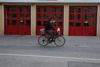 A man wears a face mask on his bicycle in central capital Nicosia, Cyprus, Wednesday, Jan. 27, 2021. Cyprus' health minister Constantinos Ioannou said that the first to re-open as of Feb. 1st will be hair and beauty salons followed a week later by retail stores, shopping malls and elementary schools. Students in their final year of high school will also go back to classes on Feb. 8. (AP Photo/Petros Karadjias)