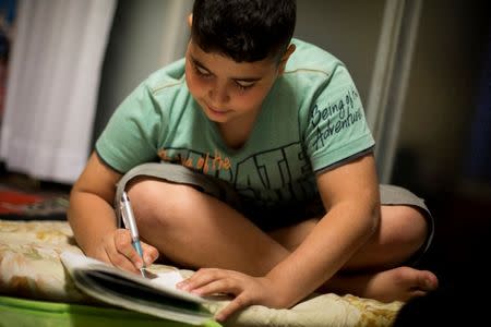 Kurdish boy Ozgur Cinaroglu, 12, who is on provisional release, does his home work in his home in Warabi, north of Tokyo October 4, 2015. REUTERS/Thomas Peter