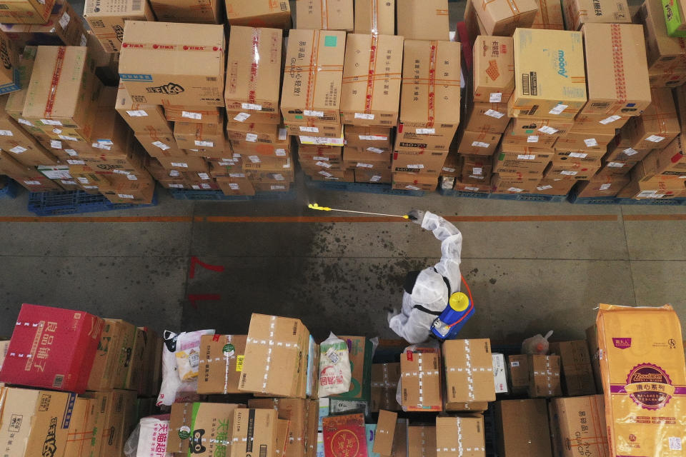 In this photo released by Xinhua News Agency, a worker wearing a protective suit sprays disinfectant the goods at a logistic distribution center in Shijiazhuang in north China's Hebei province on Saturday, Jan. 23, 2021. A Chinese city has brought 2,600 temporary treatment rooms online as the country's north battles new clusters of coronavirus. (Mu Yu/Xinhua via AP)