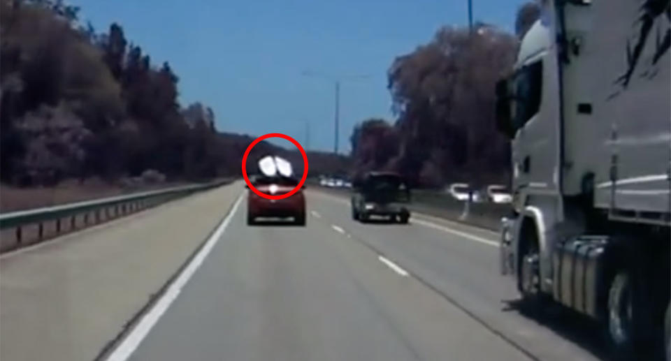 A red Range Rover is seen driving along the Pacific Motorway at Burleigh Heads with two surfboards attached to its roof racks. Source: Dash Cam Australia / Facebook