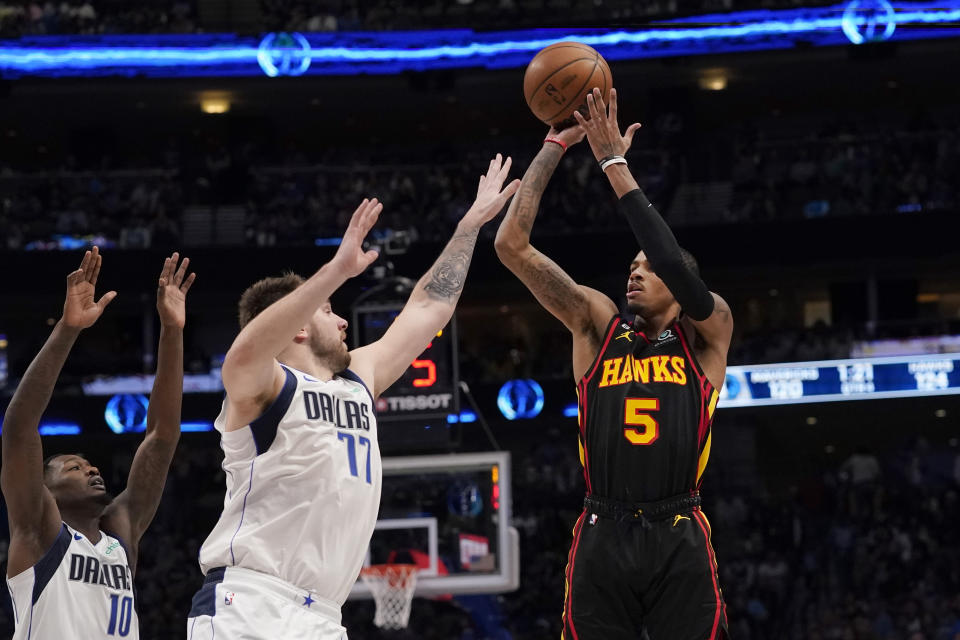 Atlanta Hawks guard Dejounte Murray (5) shoots against Dallas Mavericks defenders Luka Doncic (77) and Dorian Finney-Smith (10) during the second half of an NBA basketball game in Dallas, Wednesday, Jan. 18, 2023. Hawks won 130-122. (AP Photo/LM Otero)