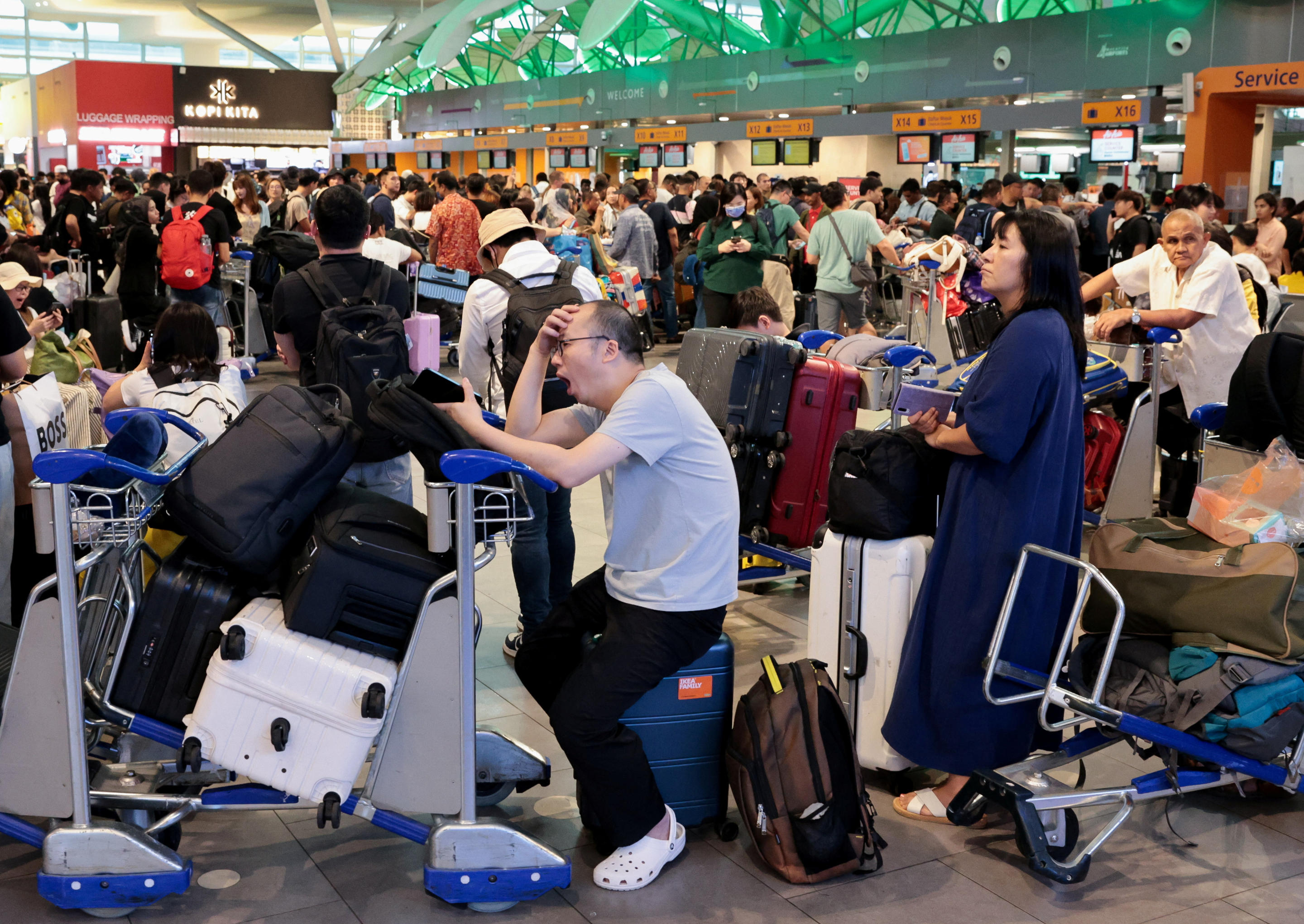 AirAsia passengers wait to be manually checked in at Kuala Lumpur International Airport.