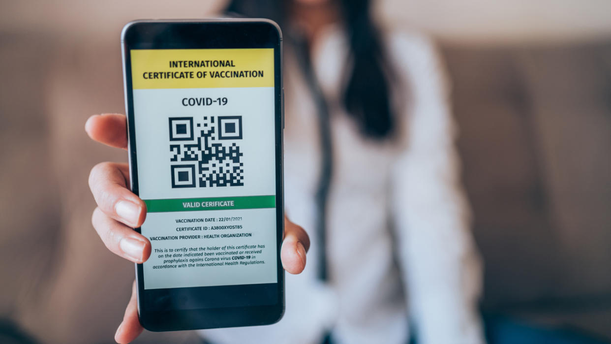 A woman presents a smartphone with a valid digital international vaccination certificate for COVID-19