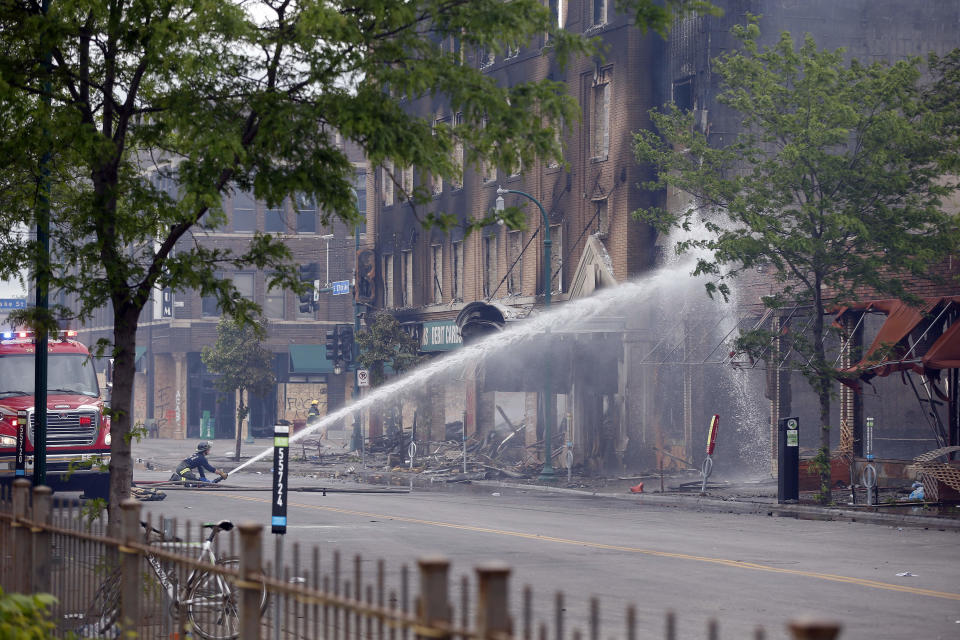 A firefighter directs water on a burned building, Friday, May 29, 2020 after another night of protests, fires and looting over the arrest of George Floyd who died in police custody Monday night in Minneapolis after video shared online by a bystander showed a white officer kneeling on his neck during his arrest as he pleaded that he couldn't breathe. (AP Photo/Jim Mone)